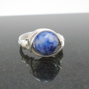 May include: A silver wire wrapped ring with a blue and white stone.