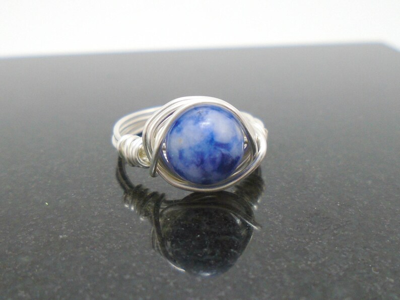 May include: A silver wire wrapped ring with a blue and white stone.