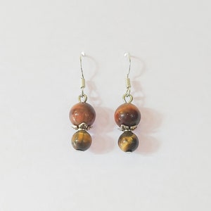May include: A pair of silver dangle earrings with two brown tiger's eye beads on each earring.