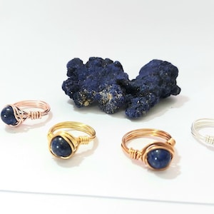 K&ouml;nnte beinhalten: Vier drahtgewickelte Ringe mit blauen Lapislazuli-Edelsteinen. Die Ringe sind in verschiedenen Metalloberfl&auml;chen erh&auml;ltlich: Ros&eacute;gold, Gold, Kupfer und Silber.