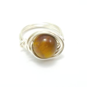 May include: A silver wire wrapped ring with a brown tiger's eye gemstone.