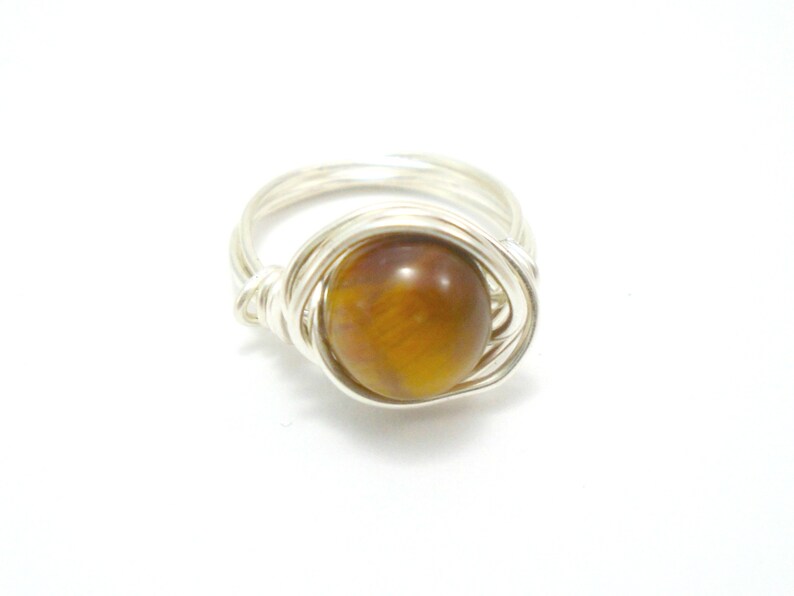 May include: A silver wire wrapped ring with a brown tiger's eye gemstone.