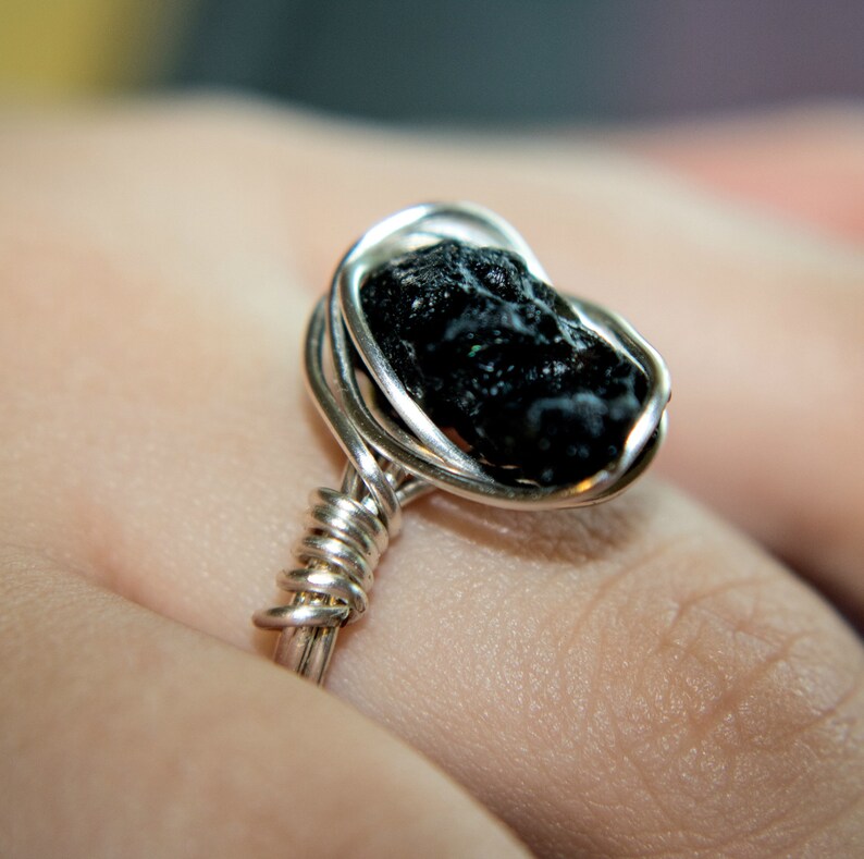 May include: A silver wire wrapped ring with a black obsidian stone.