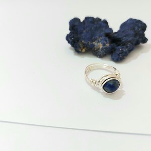 K&ouml;nnte beinhalten: Ein Ring aus Silberdraht mit einem dunkelblauen Edelstein.