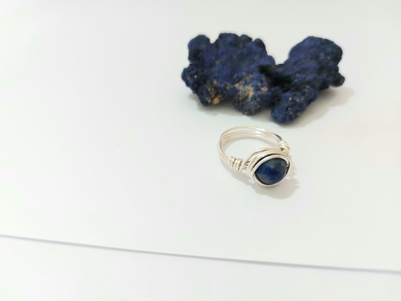 K&ouml;nnte beinhalten: Ein Ring aus Silberdraht mit einem dunkelblauen Edelstein.