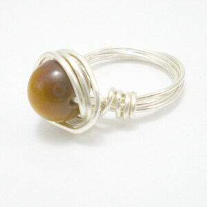 May include: A silver wire wrapped ring with a brown tiger's eye gemstone.