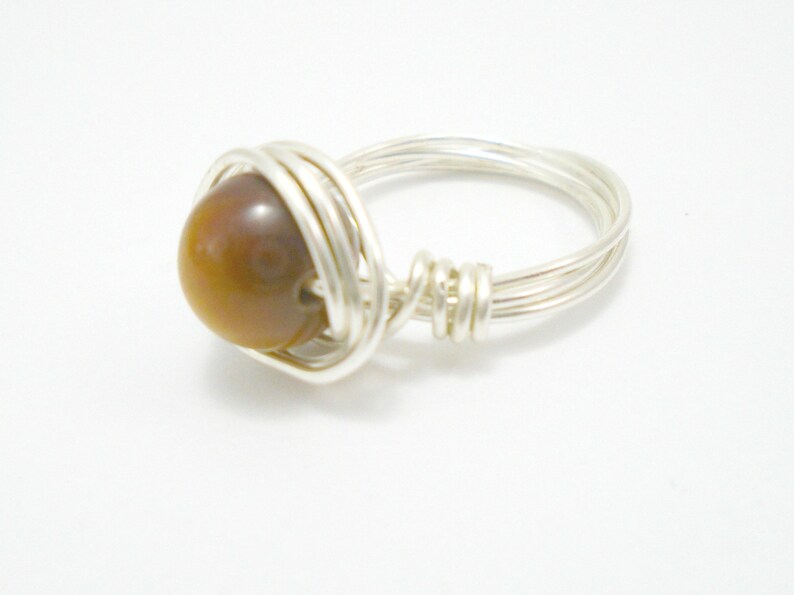 May include: A silver wire wrapped ring with a brown tiger's eye gemstone.