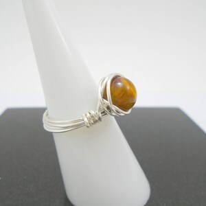 May include: A silver wire wrapped ring with a brown and gold tiger's eye stone.