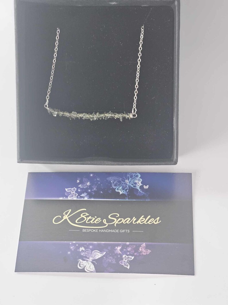 May include: A silver chain necklace with a bar pendant made of green gemstone chips. The necklace is displayed in a black box with a card that reads "K-Stie Sparkles - Bespoke Handmade Gifts".