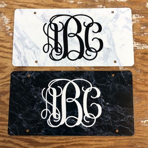 May include: Two rectangular license plate style signs with a marble pattern. The top sign has a white marble pattern with black monogram letters "ABC". The bottom sign has a black marble pattern with white monogram letters "ABC".