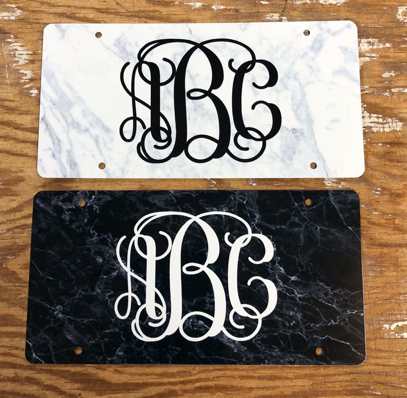 May include: Two rectangular license plate style signs with a marble pattern. The top sign has a white marble pattern with black monogram letters "ABC". The bottom sign has a black marble pattern with white monogram letters "ABC".