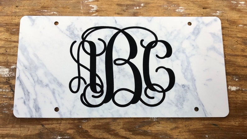 May include: White marble background with black monogram letters "ABC" in a cursive font.