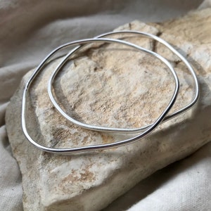 A pair of organic form bangles in recycled silver