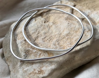 A pair of organic form bangles in recycled silver