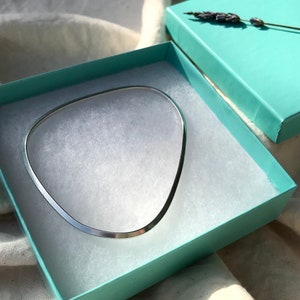 May include: A silver bangle bracelet in a light blue gift box with white tissue paper.