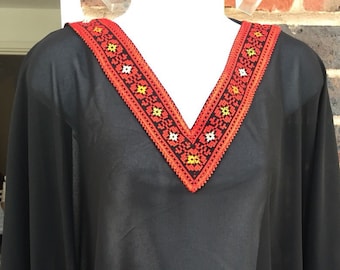May include: Black sheer tunic with red and yellow embroidered trim around the neckline and sleeves.