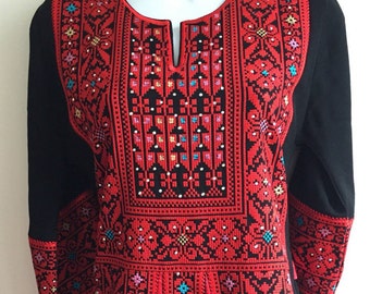 May include: A long-sleeved black dress with red embroidery. The embroidery features intricate floral patterns in red, blue, and white.