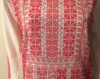 May include: White long-sleeved shirt with a red embroidered pattern. The embroidery features a geometric design with small red squares and diamonds.