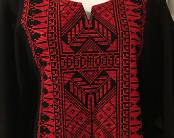 May include: Black tunic with red embroidered geometric patterns.