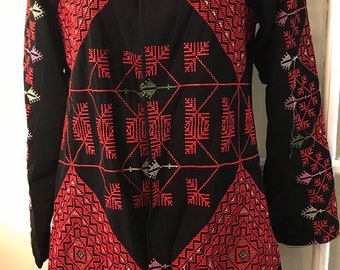 May include: A black long-sleeved jacket with intricate red and green embroidery in a geometric pattern.