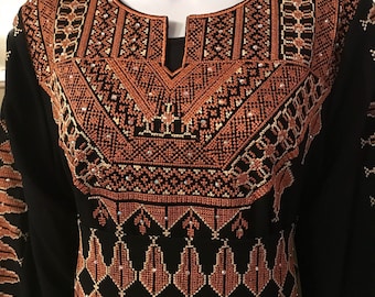 May include: Black abaya with intricate orange and white embroidery. The embroidery features geometric patterns and floral motifs.