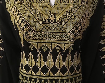 May include: Black dress with gold embroidery and embellishments. The embroidery features geometric patterns and floral motifs.