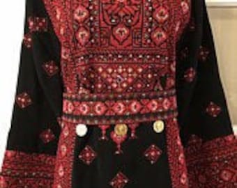 May include: A black embroidered dress with red and silver thread. The dress has a round neckline and long sleeves. The embroidery features geometric patterns and coins.