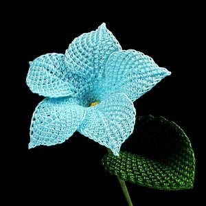 Peut inclure: Une fleur bleue en crochet avec une feuille verte en crochet. La fleur a un design &agrave; cinq p&eacute;tales et un centre jaune.