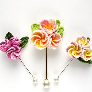 May include: Three crocheted flower hair pins with pearl accents. The flowers are pink, white, and yellow.