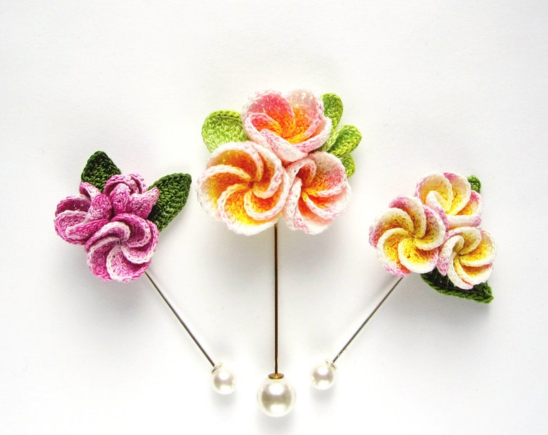 May include: Three crocheted flower hair pins with pearl accents. The flowers are pink, white, and yellow.