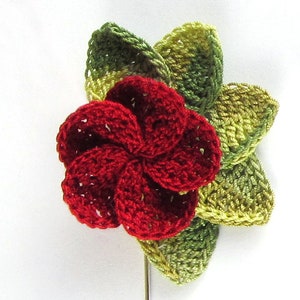 May include: A red crocheted flower with green crocheted leaves. The flower is a five-petal design and the leaves are a four-petal design.