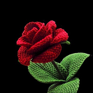 May include: A crocheted red rose with green leaves. The rose is made with yarn and is a handmade craft.