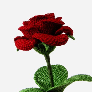 May include: A crocheted red rose with green leaves and stem.