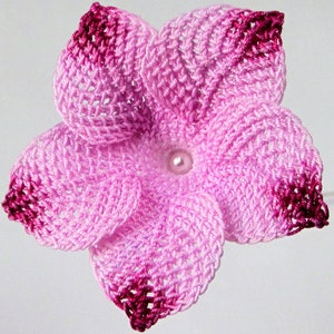 Peut inclure: Une fleur crochet&eacute; rose et bordeaux avec une perle au centre.