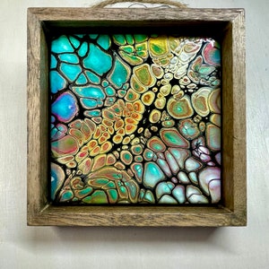 May include: A framed abstract painting with a black background and a swirling pattern of turquoise, gold, and pink colors.