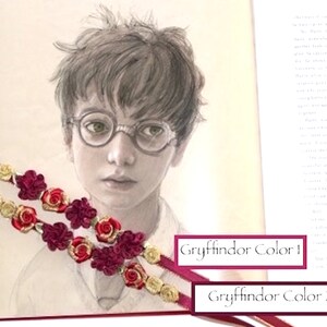 May include: A close-up of a drawing of a young boy with brown hair and glasses. The drawing is on a page of a book with two red and gold ribbon bookmarks. The bookmarks have the text "Gryffindor Color 1" and "Gryffindor Color 2".