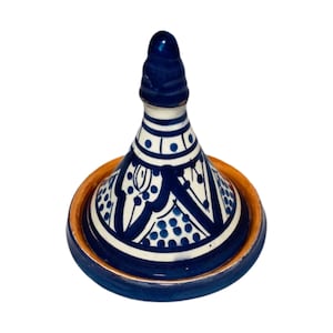May include: A blue and white ceramic tagine with a conical lid and a decorative pattern. The tagine is a traditional Moroccan cooking pot.