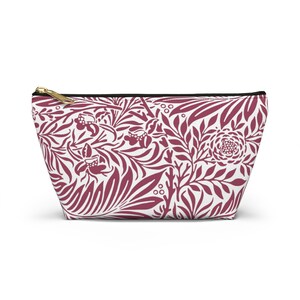 May include: A burgundy floral patterned zippered pouch. The pouch is made of a white fabric with a burgundy floral pattern.