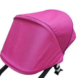 May include: A pink stroller canopy made of a soft, breathable fabric. The canopy is designed to provide shade and protection from the sun and wind.