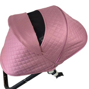 May include: A pink quilted stroller canopy with a black mesh window. The canopy has a zipper on the side.