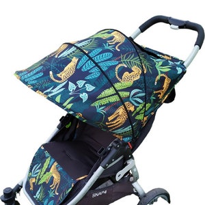 May include: A black stroller with a green, yellow, and orange canopy featuring a jungle print with leopards and leaves. The stroller has a black seat and a silver frame. The stroller has the text "SNAP4" on the side.