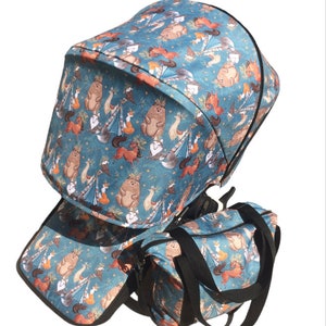 May include: A blue stroller canopy and matching diaper bag with a woodland animal print featuring bears, foxes, and deer. The print has a whimsical, hand-drawn style.