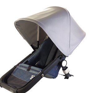 May include: A black stroller with a gray canopy and a denim seat. The stroller has a black handle and a black frame.