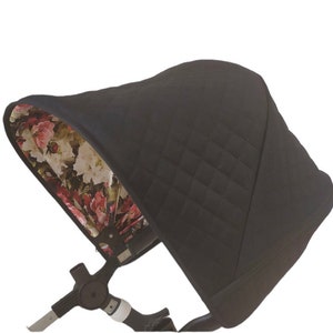 May include: Black stroller canopy with a floral pattern lining. The canopy is quilted and has a black exterior.