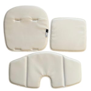Puede incluir: Juego de tres cojines crema para trona de bebé. El juego incluye un cojín para el asiento, otro para el respaldo y un tercero para la entrepierna. Los cojines están hechos de un material suave y liso, diseñados para bebés y niños pequeños.