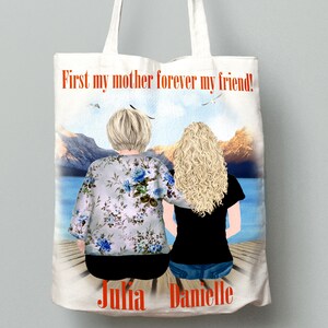 May include: White tote bag with a watercolor illustration of two women sitting on a dock overlooking a lake. The text "First my mother forever my friend!" is printed in orange at the top of the bag. The names "Julia" and "Danielle" are printed at the bottom of the bag.