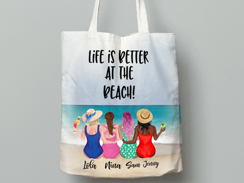 May include: A white tote bag with the text "Life is better at the beach!" printed on it. The bag features a colourful illustration of four women in swimsuits and hats on a beach with drinks in their hands. The names "Lola, Nina, Sam, Jenny" are printed below the illustration.