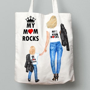 Op de afbeelding: Witte tote bag met een zwarte kroon en de tekst "My Mom Rocks" aan de ene kant en een vrouw en kind die witte shirts dragen met de tekst "My Kid Rocks" aan de andere kant.
