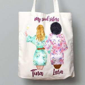 K&ouml;nnte beinhalten: Wei&szlig;e Einkaufstasche mit einer Grafik von zwei Frauen in Roben mit dem Text "my soul sisters" und den Namen "Tina" und "Lara" darunter.