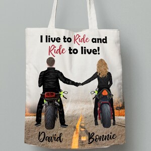 Pu&ograve; includere: Borsa tote bianca con un'illustrazione in bianco e nero di una coppia in moto. Il testo "I live to Ride and Ride to live!" &egrave; stampato in rosso sulla borsa. I nomi "David" e "Bonnie" sono stampati sotto la coppia.